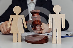 Lawyer or counselor holds gavel behind of figures of young family, divorce and law concept