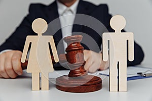 Lawyer or counselor holds gavel behind of figures of young family, divorce or separation concept