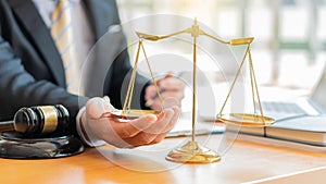 The lawyer grasps the scales that are placed on the table so that they do not tilt in one direction.