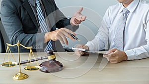 Lawyer hand holding pen and providing legal consult business dispute service at the office with justice scale and gavel hammer