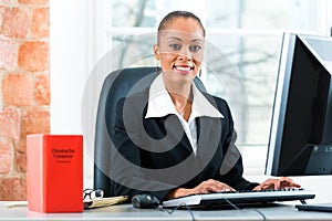 Lawyer in her office with law book on computer