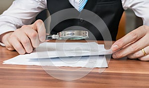 Lawyer is inspecting or analysing legal agreement with magnifying glass