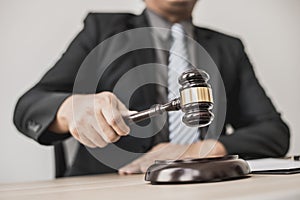 A lawyer or legal advisor holding a small hammer for a judge`s table in court is about to pound on the podium to deliver