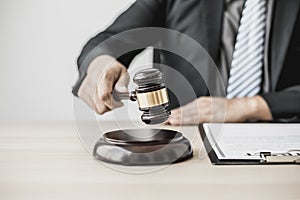 A lawyer or legal advisor holding a small hammer for a judge`s table in court is about to pound on the podium to deliver a fair