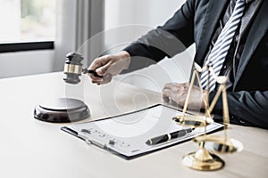 A lawyer or legal advisor holding a small hammer for a judge`s table in court is about to pound on the podium to deliver a fair