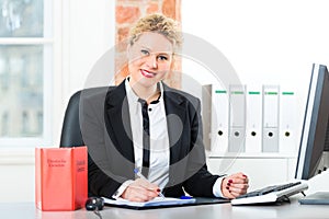 Lawyer in office with law book working on desk