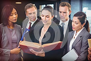 Lawyer reading law book and interacting with business people