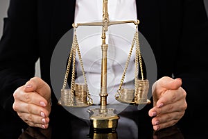 Lawyer`s Hand Protecting Justice Scale With Coins