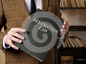 Lawyer in suit holds Defamation law book. photo