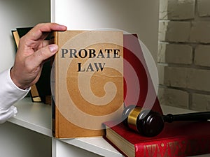Lawyer takes a book Probate law from a shelf. photo