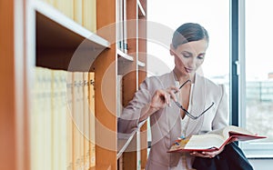 Lawyer woman reading in the library of the law firm