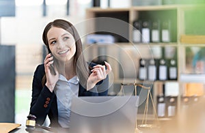 Lawyer woman talking mobile phone and working on tablet and laptop on table in office.