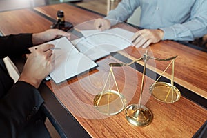 Lawyer working with client discussing contract papers with brass scale about legal legislation in courtroom, consulting to help