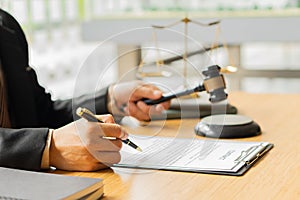 A lawyer working in an office and a judge`s hammer and gold scales in front with a notebook on a legal advisor concept table.