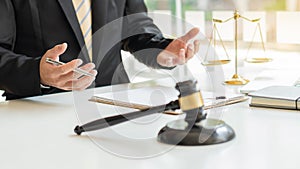 Lawyers discuss the brass-scale contract document on the wooden table in the law firm for advice on the concept of justice.