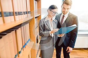 Lawyers in library of law firm discussing strategy in a case holding file