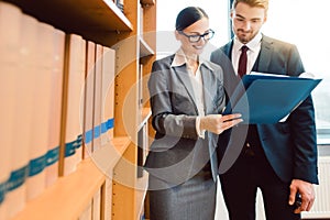 Lawyers in library of law firm discussing strategy in a case holding file