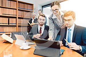 Lawyers in their law firm working on computer with books in background