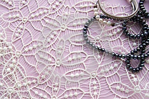 Lay Flat pink background and the gorgeous lace, glittering necklace of black pearls, and stylish bracelet. Beauty and fashion