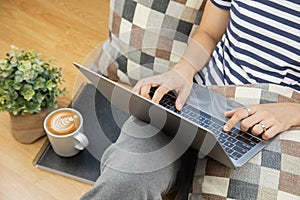 Lay flat view of asian woman working at home with laptop and black coffee on wooden floor shows concept of working from anyway by