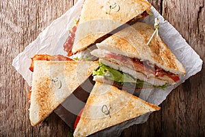 layer club sandwich with turkey meat, bacon, tomatoes and lettuce macro. Horizontal top view