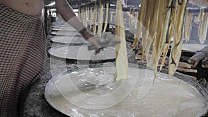 Layer forms on its surface, man using a knife to divide it into two parts and hanging tofu skin across a bamboo strip