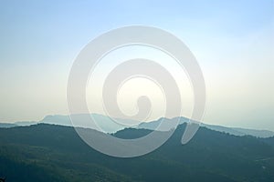 Layer of mountain peaks covered with coniferous deciduous forest