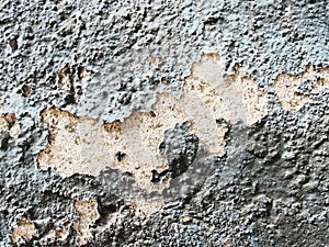 A layer of peeling old blue paint on the relief surface of a concrete cement wallTexture of old white cracked paint on blue concre