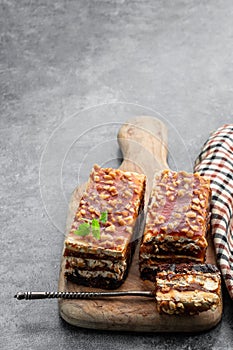 Layered cake with caramel cream and nuts on gray background