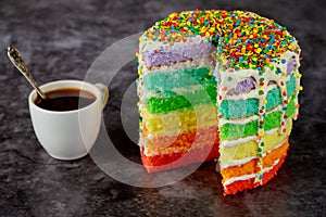 Layered delicious homemade rainbow cake with cup of coffee