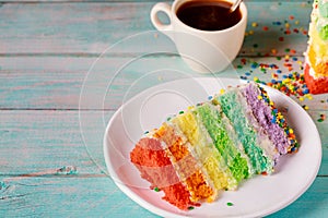 Layered delicious homemade rainbow cake with cup of coffee