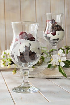 Layered dessert with chocolate cake, whipped cream and raspberry in a jar, spring flower decoration