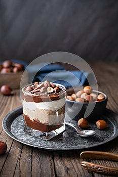 Layered dessert with chocolate mousse, cream cheese and whipped cream mixed with chestnut puree, topped with hazelnuts in a glass