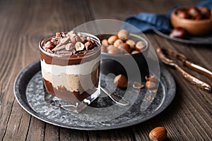 Layered dessert with chocolate mousse, cream cheese and whipped cream mixed with chestnut puree, topped with hazelnuts in a glass