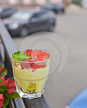 Layered dessert with fruit and cream cheese in glass jar, selective focus. Strawberry milk dessert in a small glass