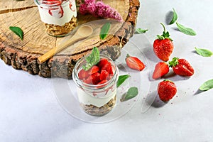 Layered dessert with strawberries, cake and cream cheese on wood background, copy space. Authentic lifestyle image