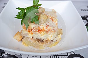 Layered fish salad herring with vegetables seasoned with mayonnaise and decorated with croutons.