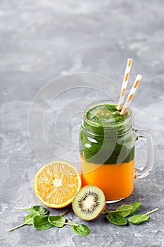 Layered healthy smoothie with spinach, kiwi, orange and mango