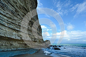 Layered rock by ocean, gorgeous ocean and mountain views, blue skies