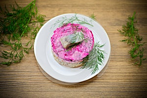 layered salad of boiled vegetables with beets and herring on a plate