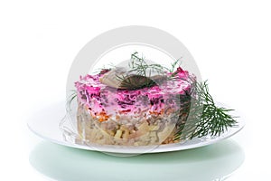 layered salad of boiled vegetables with beets and herring on a plate