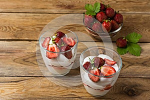 Layered strawberries cream cheese dessert on wooden background