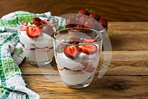Layered strawberries dessert with cream cheese on rustic wooden
