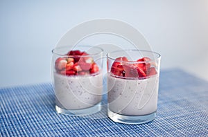 Layered strawberry homemade italian creamy dessert panna cotta with fresh berries in glass on blue background. Organic sweet. Side