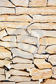 Layered surface of yellow sandstone stone with large streaks of shadow in harsh sunlight