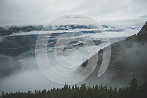 Between layers of clouds, Howe Sound appears from high above