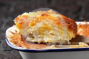 Layers of Creamy Gratin dauphinois potato with melted cheese on wooden serving spatula photo