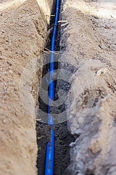 Laying a blue electrical cable in a trench in the ground. Underground communications. Electrical work at the construction site