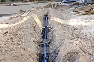 Laying a blue electrical cable in a trench in the ground. Underground communications. Electrical work at the construction site