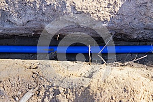 Laying a blue electrical cable in a trench in the ground. Underground communications. Electrical work at the construction site